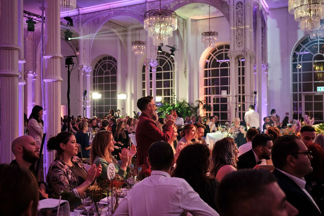 Der volle Saal der Flora Köln in violettem Licht, Gäste applaudieren im Stehen